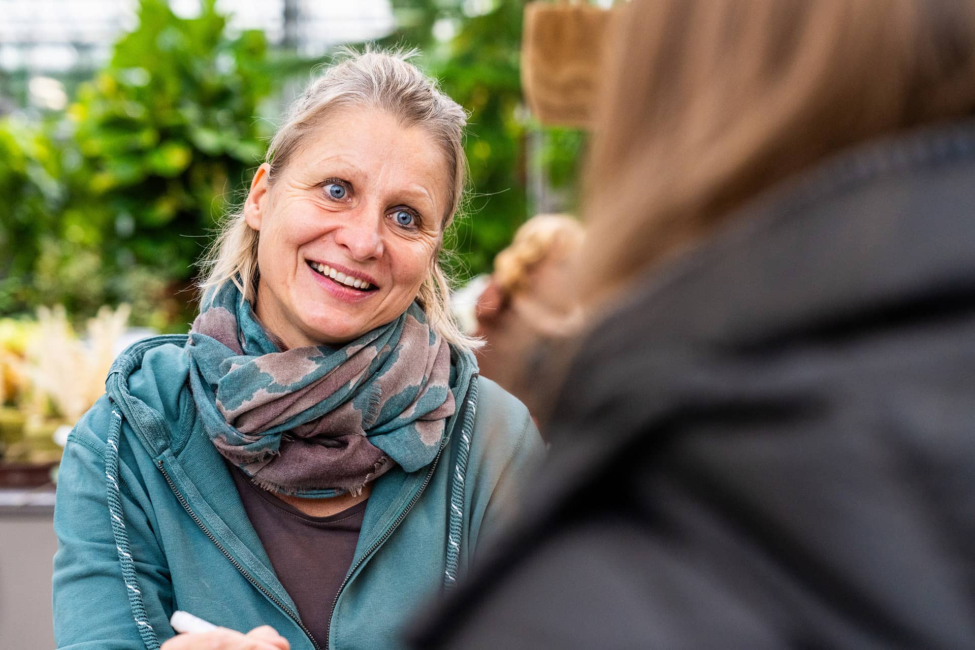 Frau spricht zu Kundin und lächelt