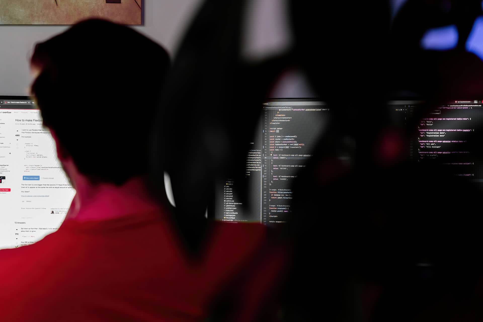 Web Entwickler sitzt vor Bildschirmen von hinten